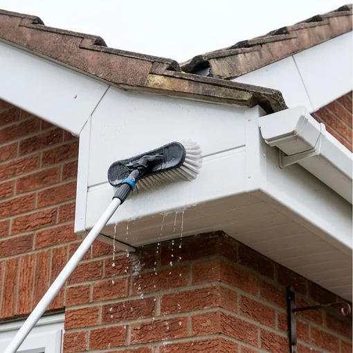 Illustrative brush washing white fascia and soffit boards on another red brick bungalow